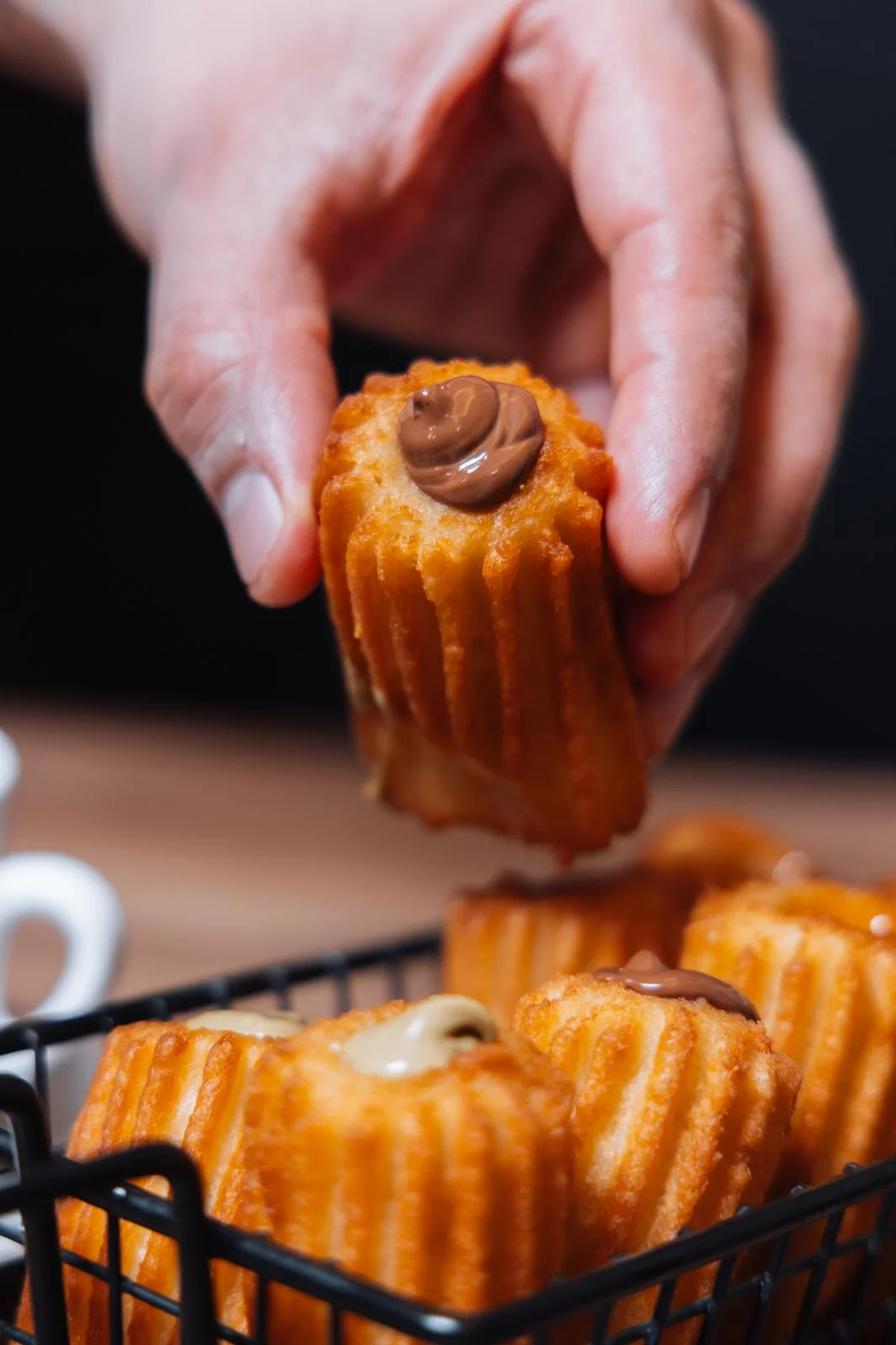 Una mano sostiene una porra rellena de crema de chocolate recién hecha