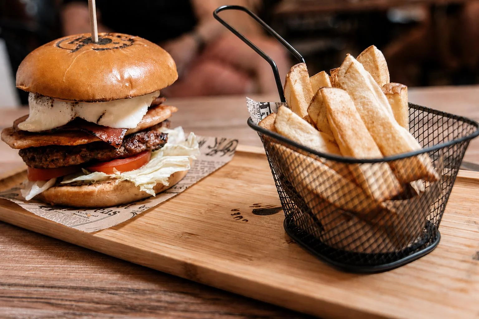 Hamburguesa artesanal con patatas caseras en cesta metálica